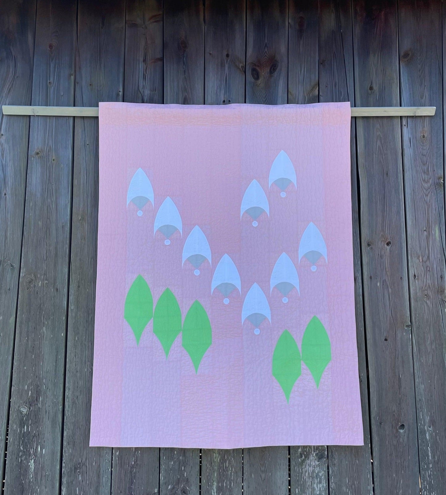 Quilt hanging on wooden background.