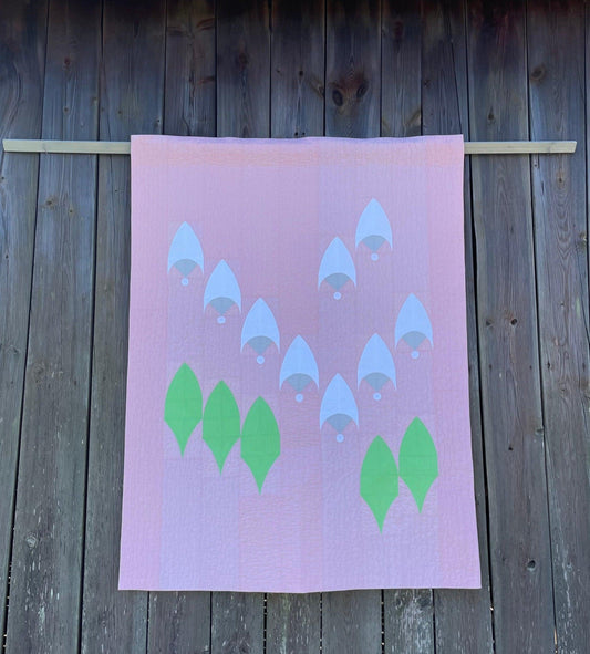 Quilt hanging on wooden background.