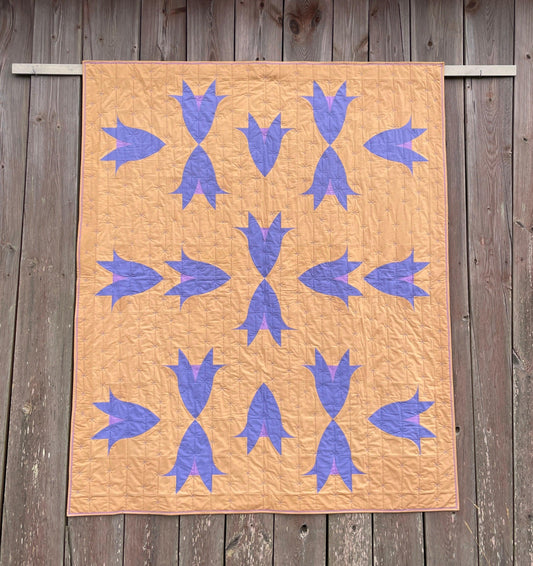 Quilt with flowers hanging on an old barn